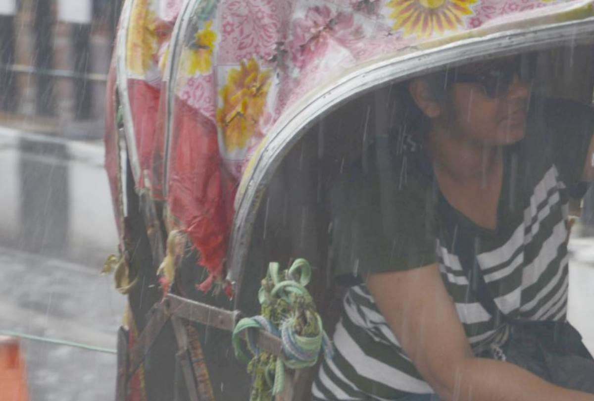 a girl opens her umbrella to save a rickshaw puller from rain