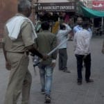 ताजमहल के पश्चिमी गेट पर पर्यटको को जबरदस्ती सामान बेचने वालों को भगाता पुलिसकर्मी