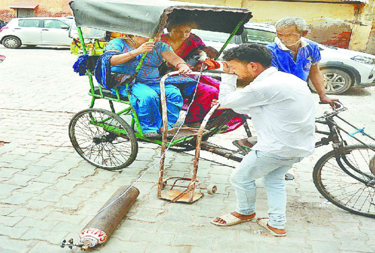 woman carrying oxygen cylinder with patient in sn medical medical agra