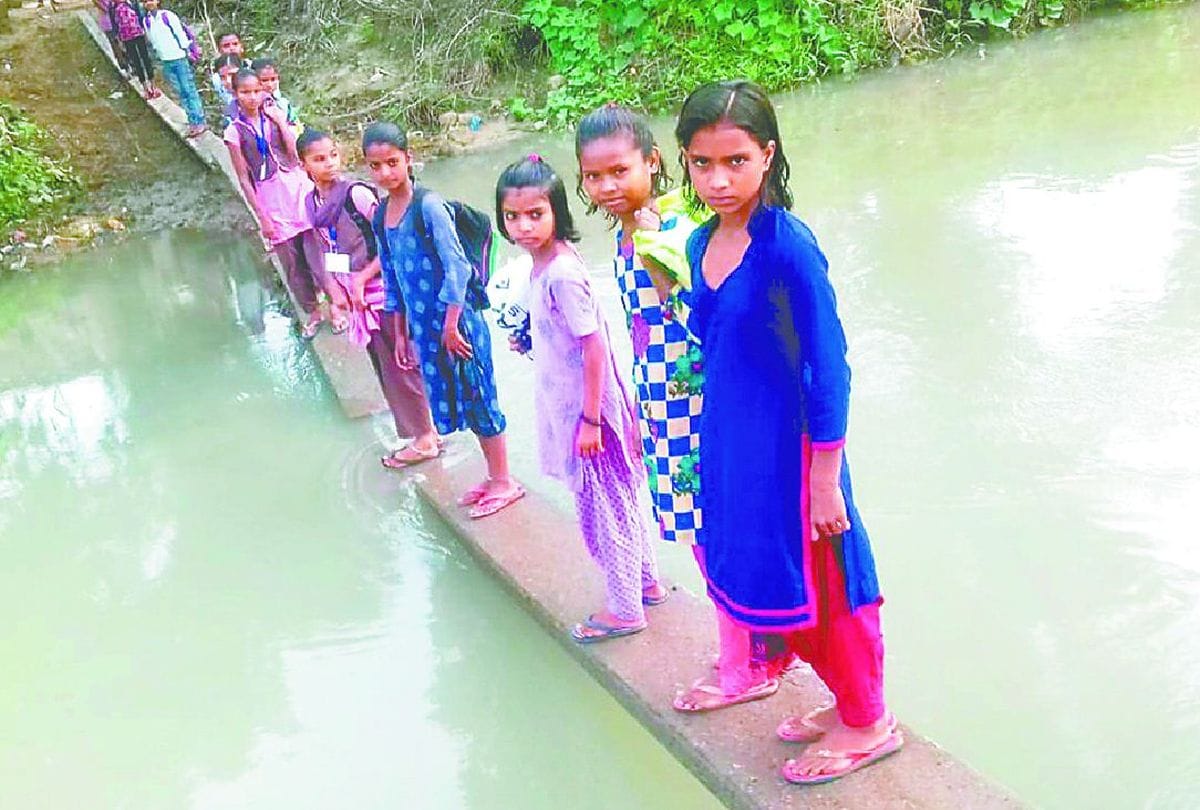 school children cross the canal by passing on electric pole in etah