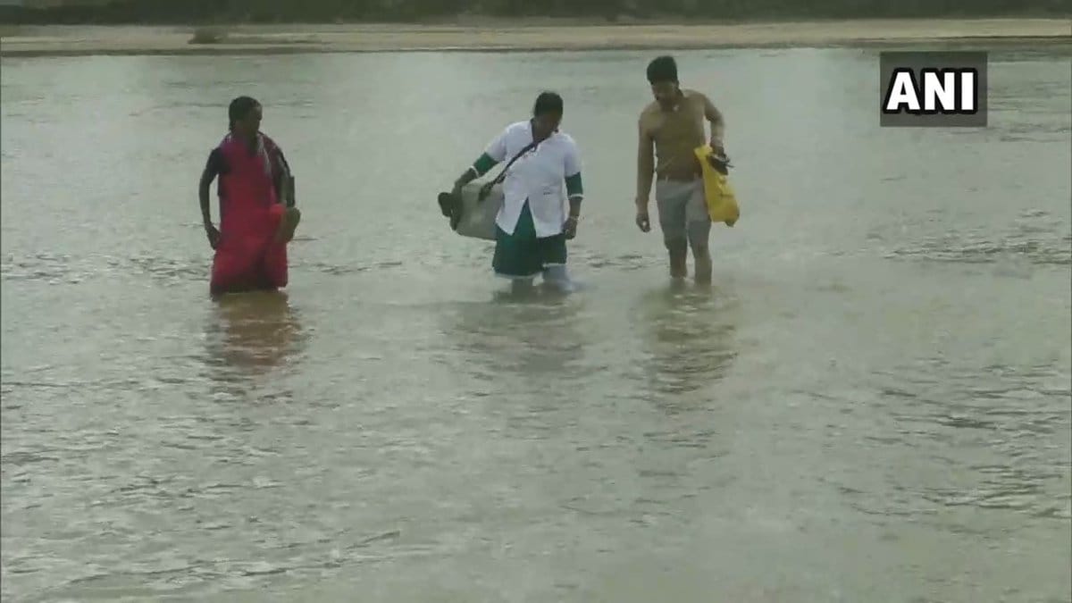 Health worker crosses a river on foot to provide healthcare service to villagers in Chhattisgarh