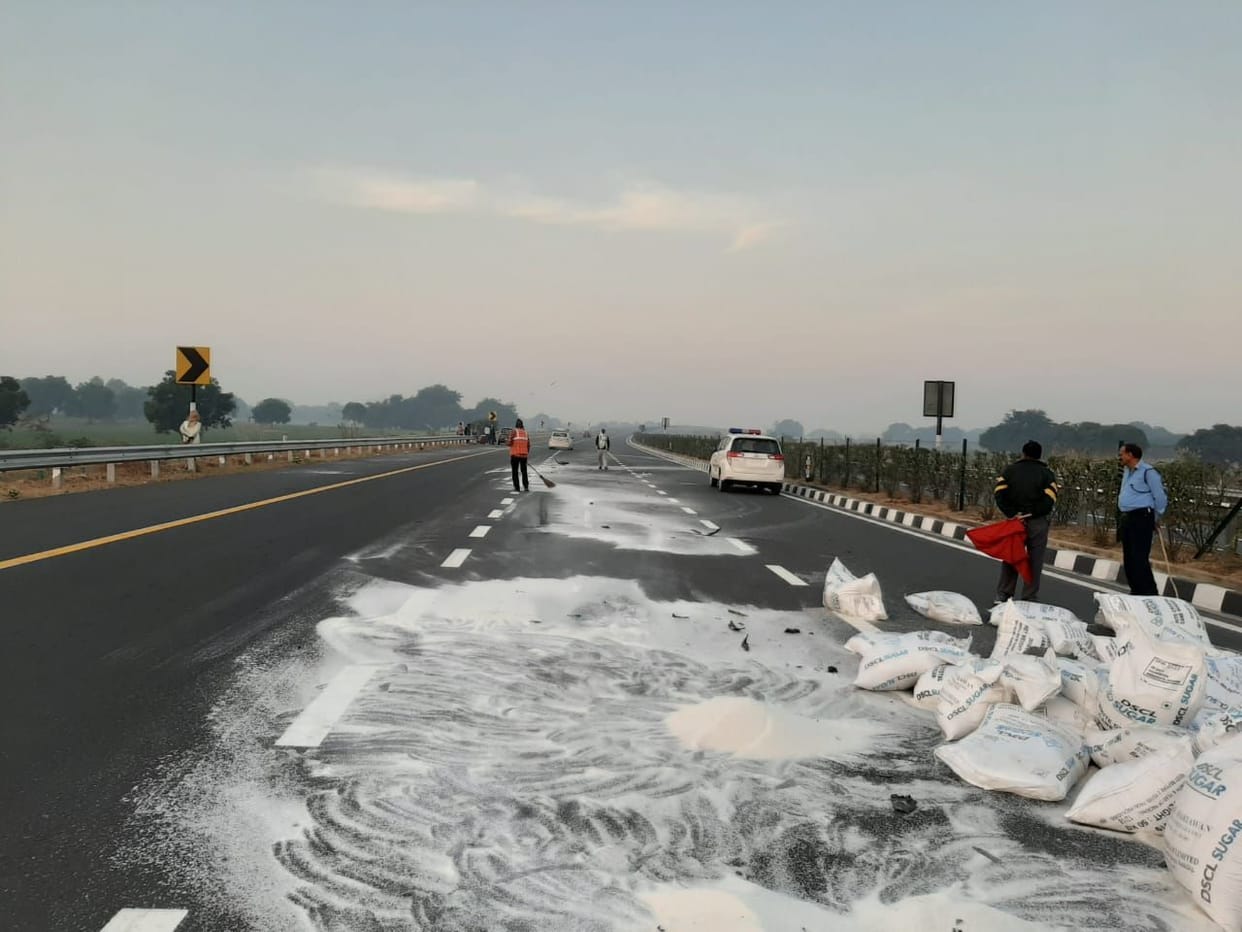 eksapres-ve par shakkar kee boriyon se bhara trak palata, machee lootamaar