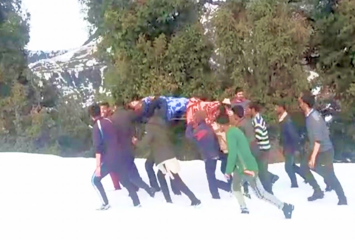 people bring the heart patient on the cot to the road on foot in snow