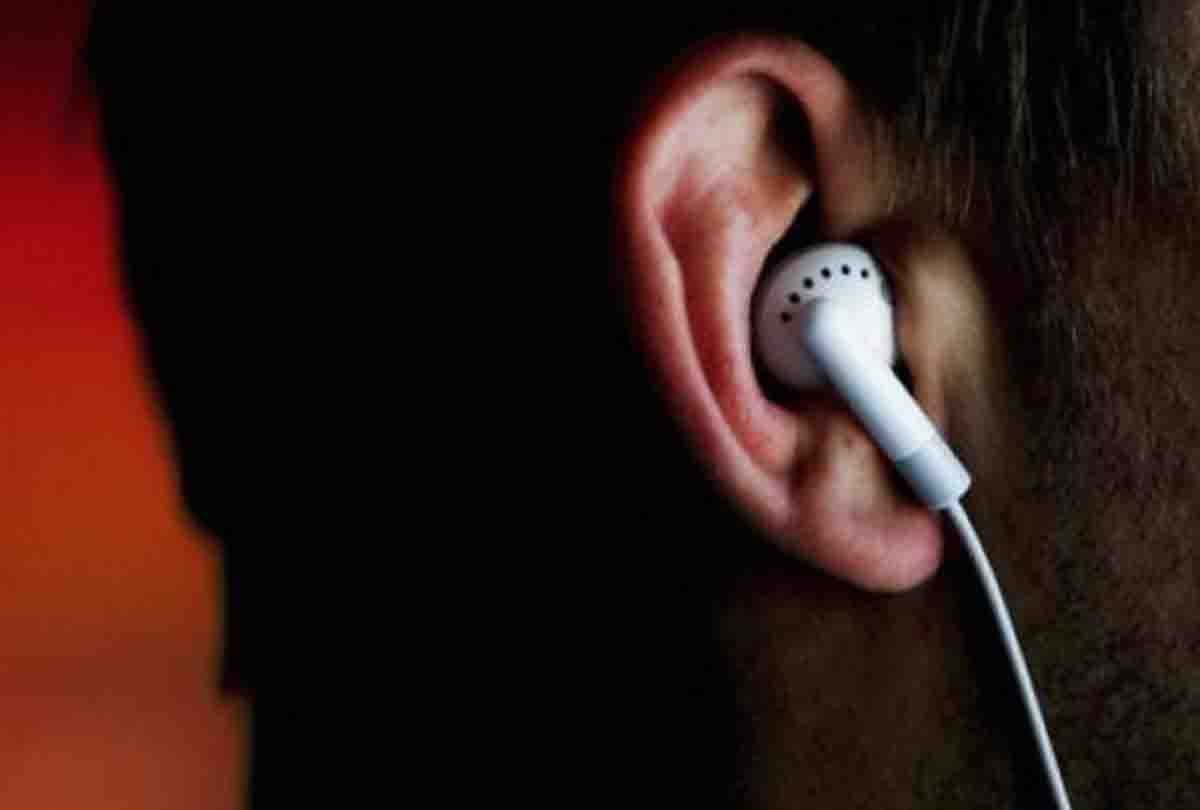 young man crossing the tracks with earphone cut off a train