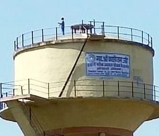 A young man climbing a water tank to fly a kite
