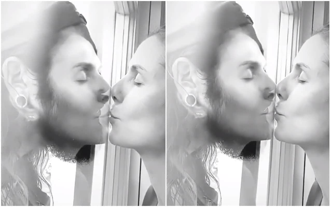 Heidi Klum kissing husband Tom Kaulitz through a glass window await coronavirus test results