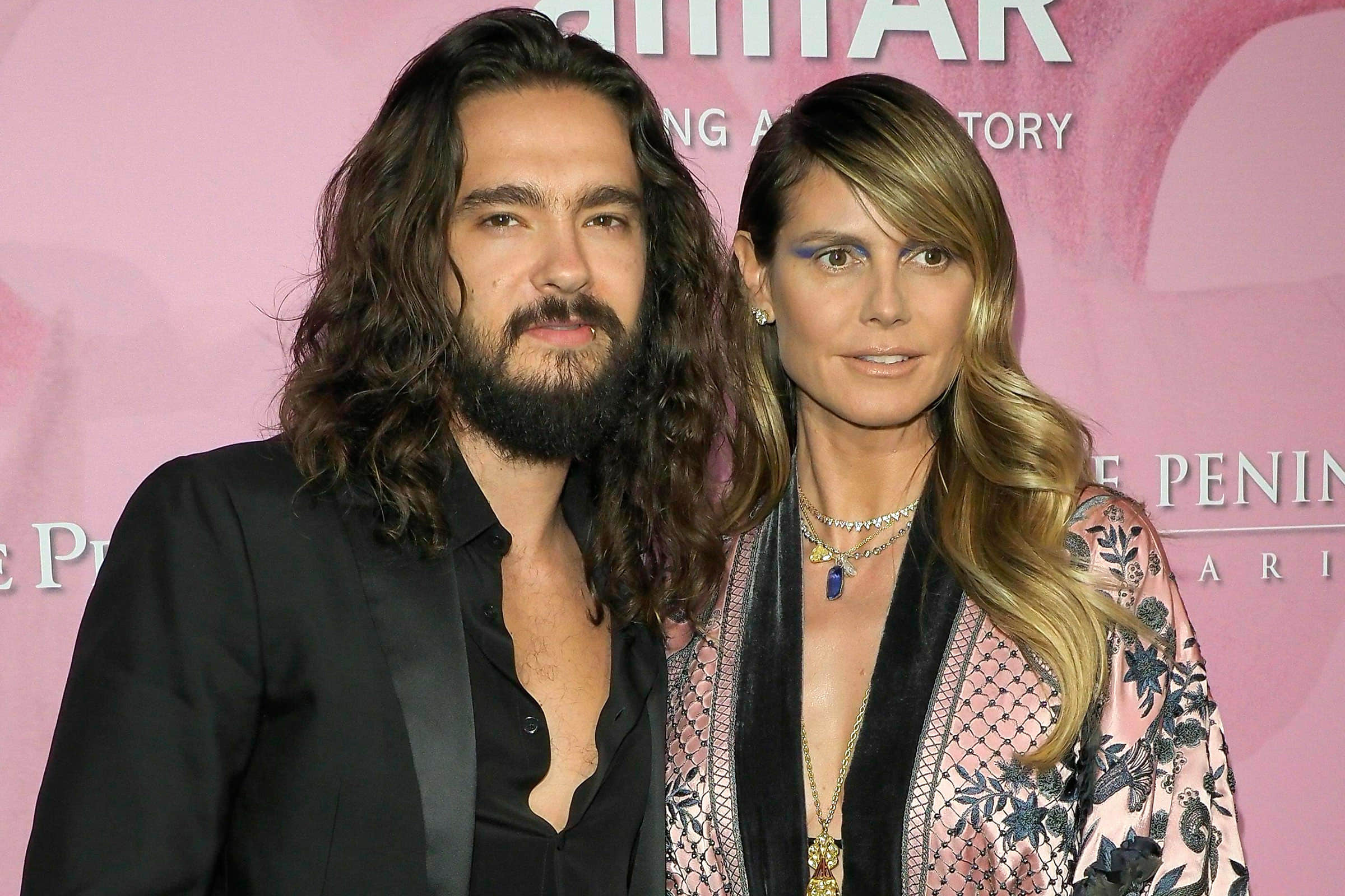 Heidi Klum kissing husband Tom Kaulitz through a glass window await coronavirus test results