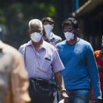 कोरोना से बचने के लिए मास्क लगाए लोग