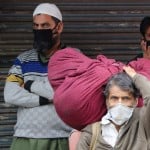 कोरोना के डर से मास्क पहने लोग