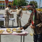 नई दिल्ली में लोगों को खाना बांटते पुलिस कर्मी।