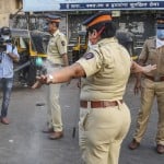 मुंबई में बांद्रा रेलवे स्टेशन के बाहर एक महिला पुलिस कर्मी की वर्दी पर दवा छिड़कता एक स्वास्थ्य कर्मी।