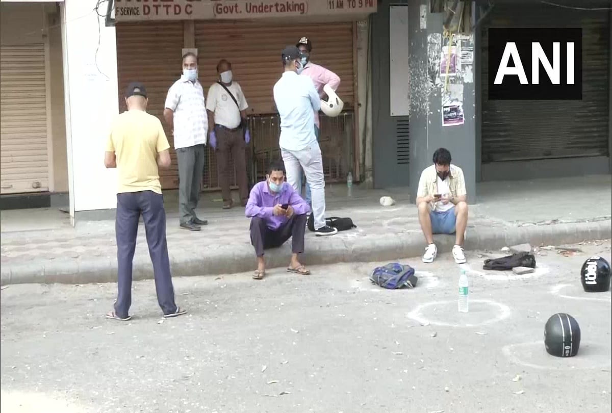 delhi e token necessary for buying liquor but unaware ppeoople still in long queue by keeping stones sacks helmets waiting their turn