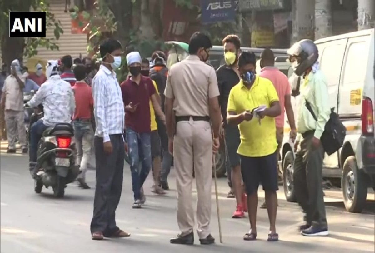 delhi e token necessary for buying liquor but unaware ppeoople still in long queue by keeping stones sacks helmets waiting their turn