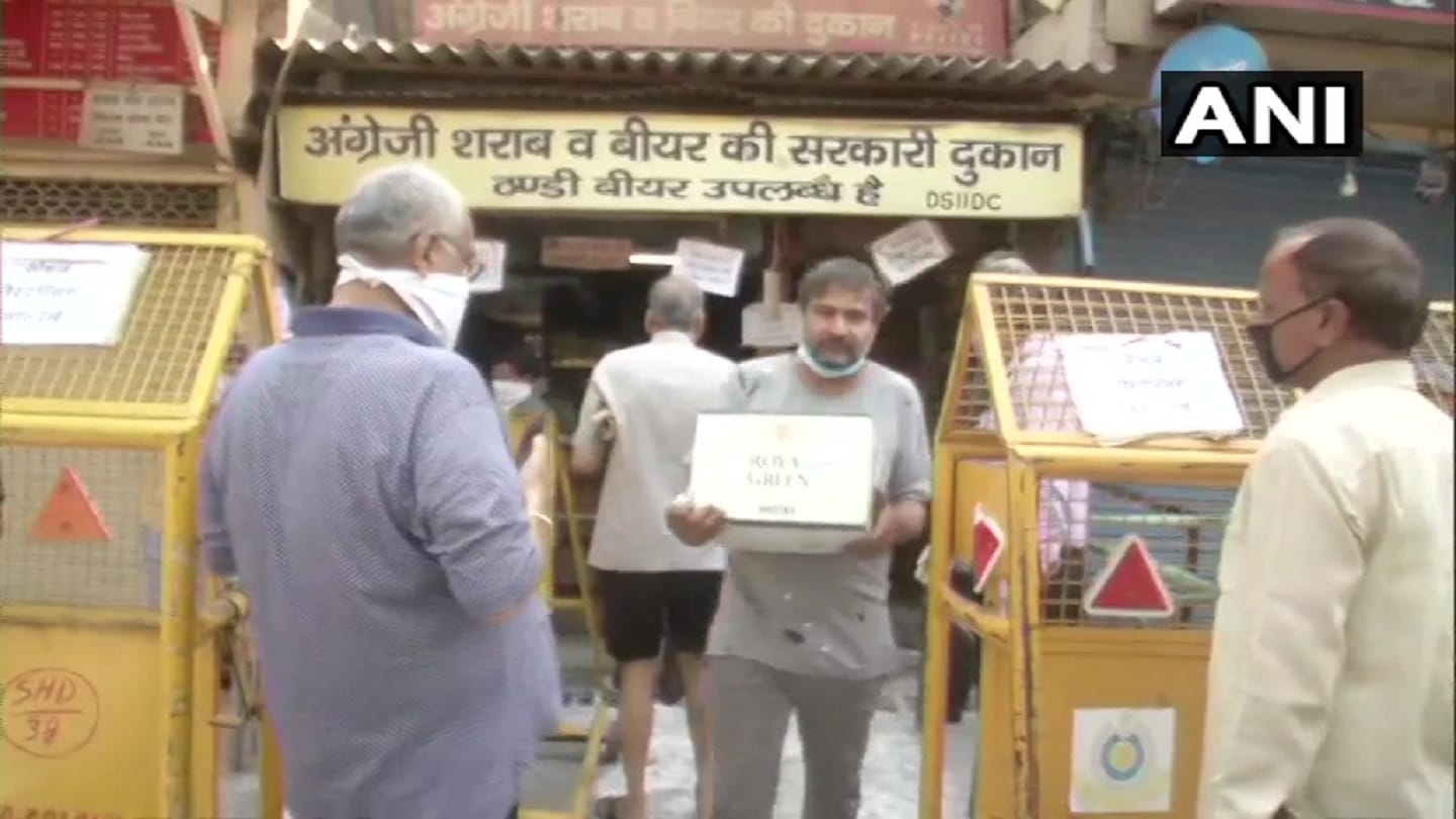 delhi e token necessary for buying liquor but unaware ppeoople still in long queue by keeping stones sacks helmets waiting their turn