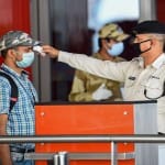 नई दिल्ली में एक शख्स के शरीर के तापमान की जांच करता सुरक्षा कर्मी।