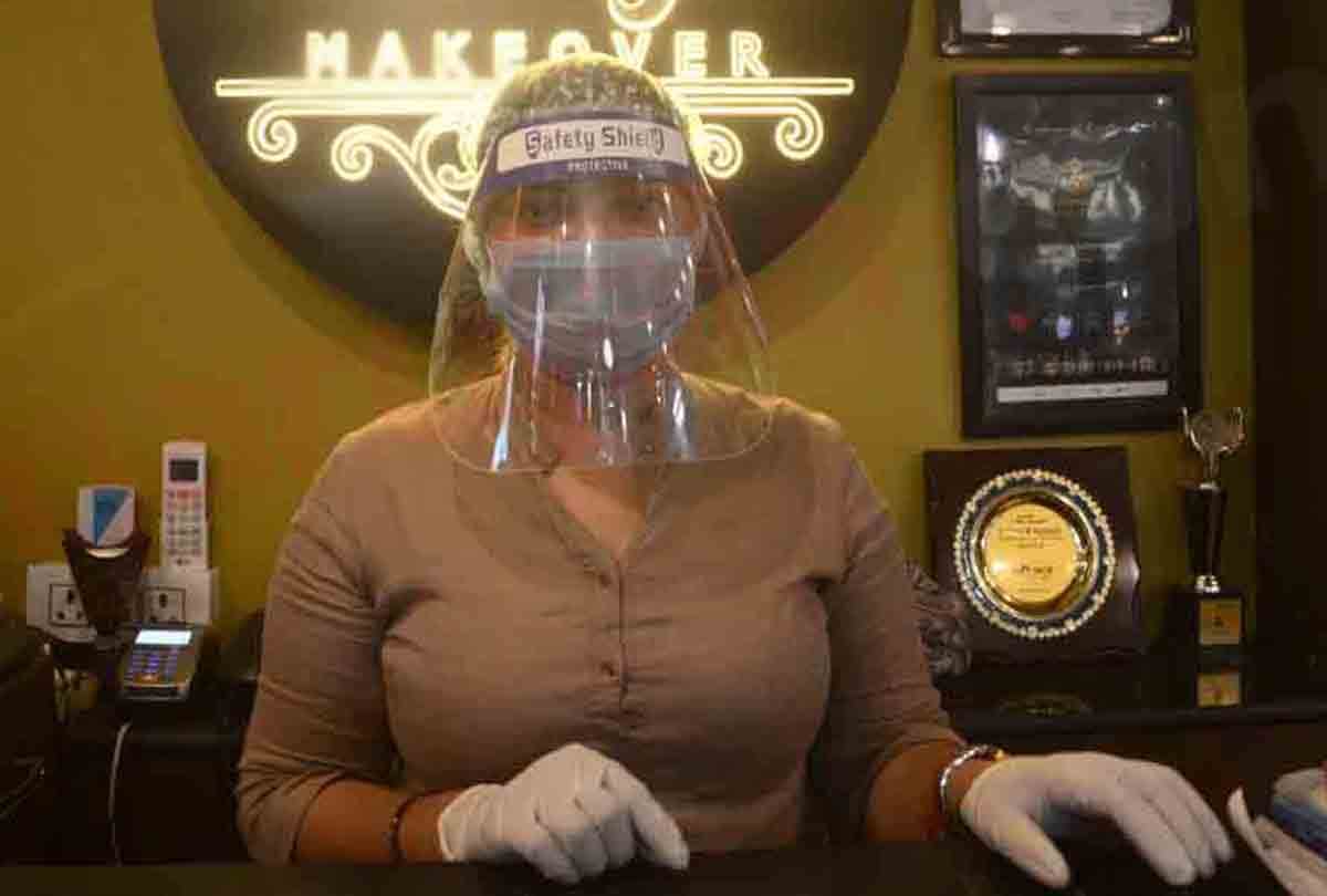 Hairdressers wearing personal protective equipment attend a customer at a hair salon