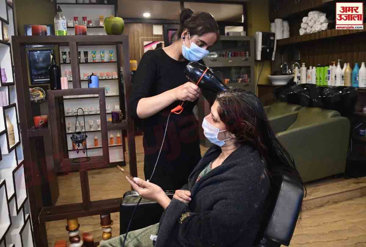 Hairdressers wearing personal protective equipment attend a customer at a hair salon