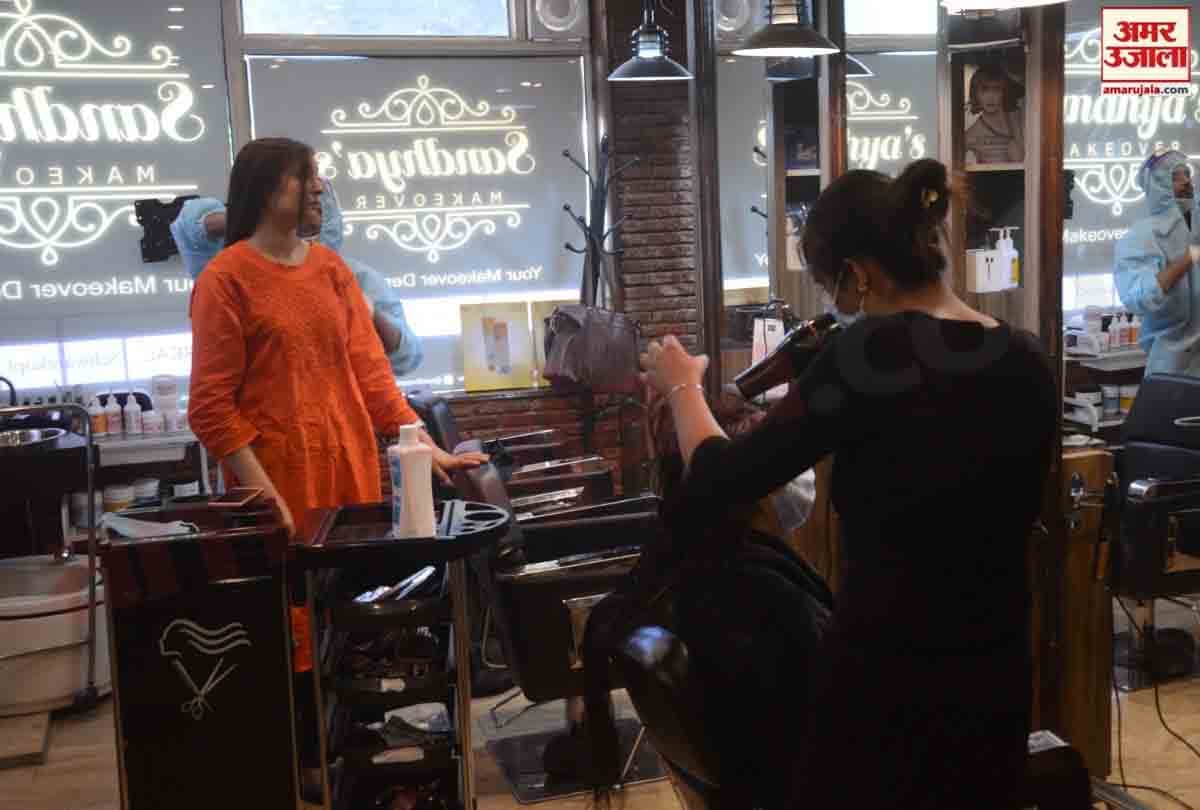 Hairdressers wearing personal protective equipment attend a customer at a hair salon
