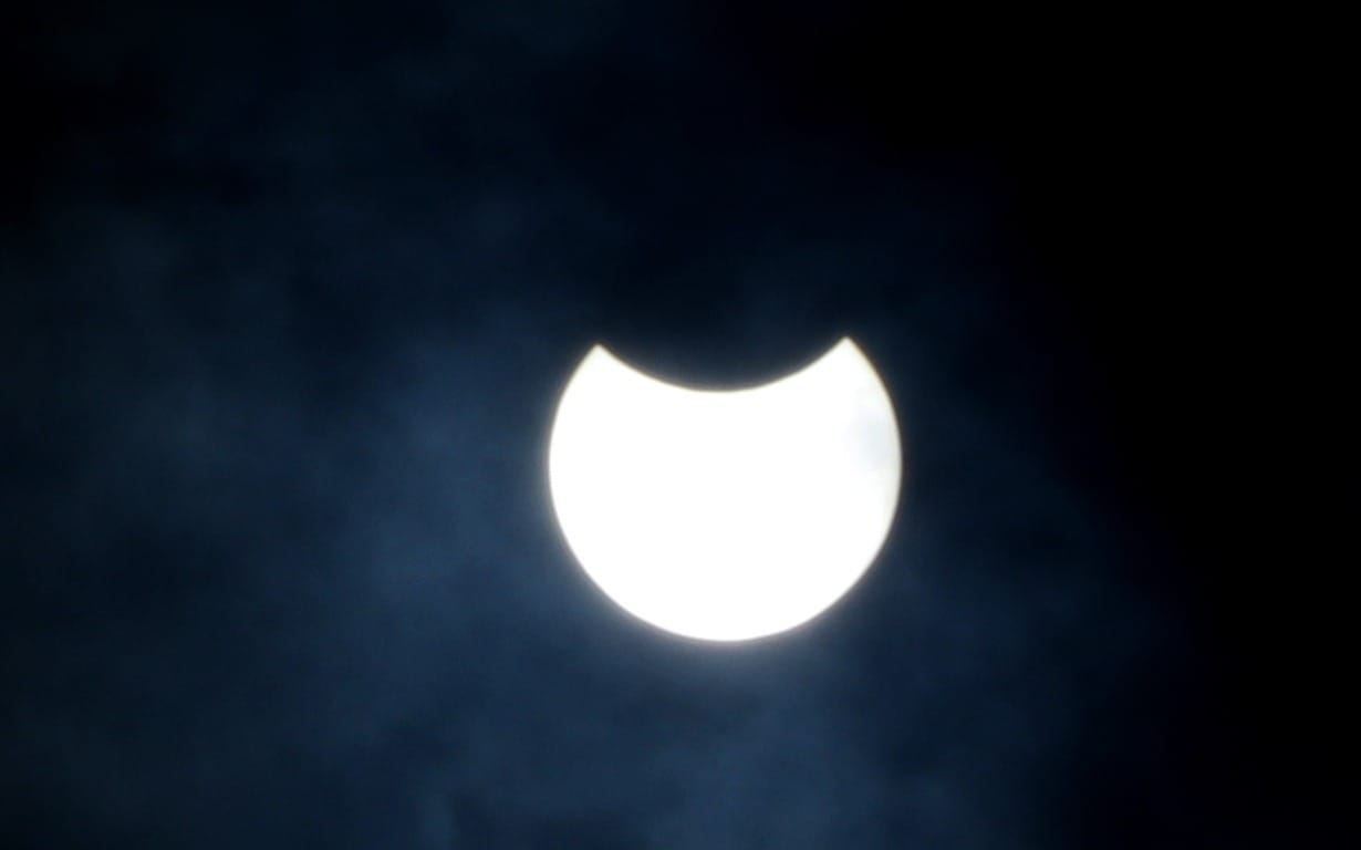 View of solar eclipse seen through filter glasses and telescopes