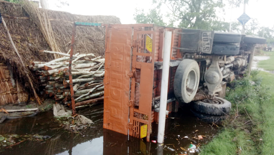 Wood-laden DCM overturned on roadside hut
