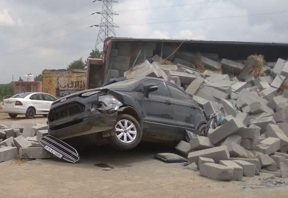 a truch which are fuill of cement make blocks overturn in car at highway