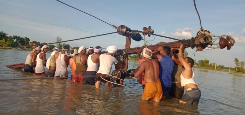 Electricity workers engaged in building a pillar in flood water
