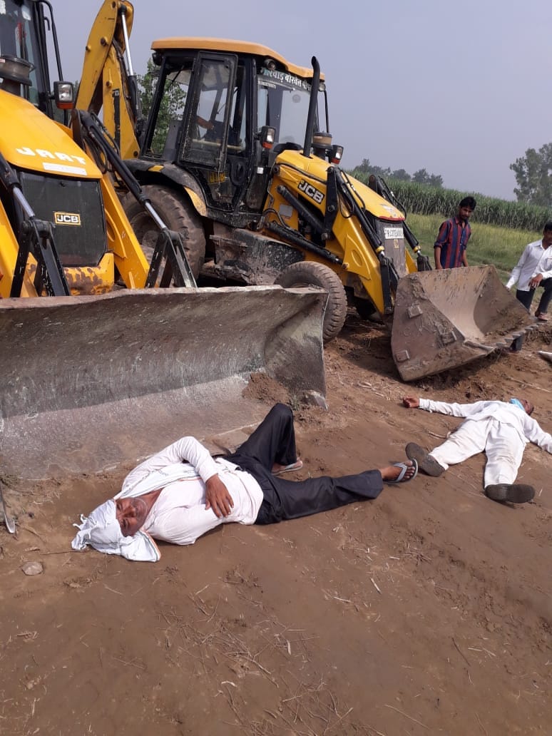 Farmers lie in front of JCB, work stopped