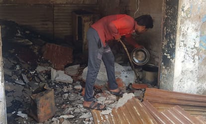 किराने की दुकान में आग लगने के बाद बचा सामान देखता दुकानदार।