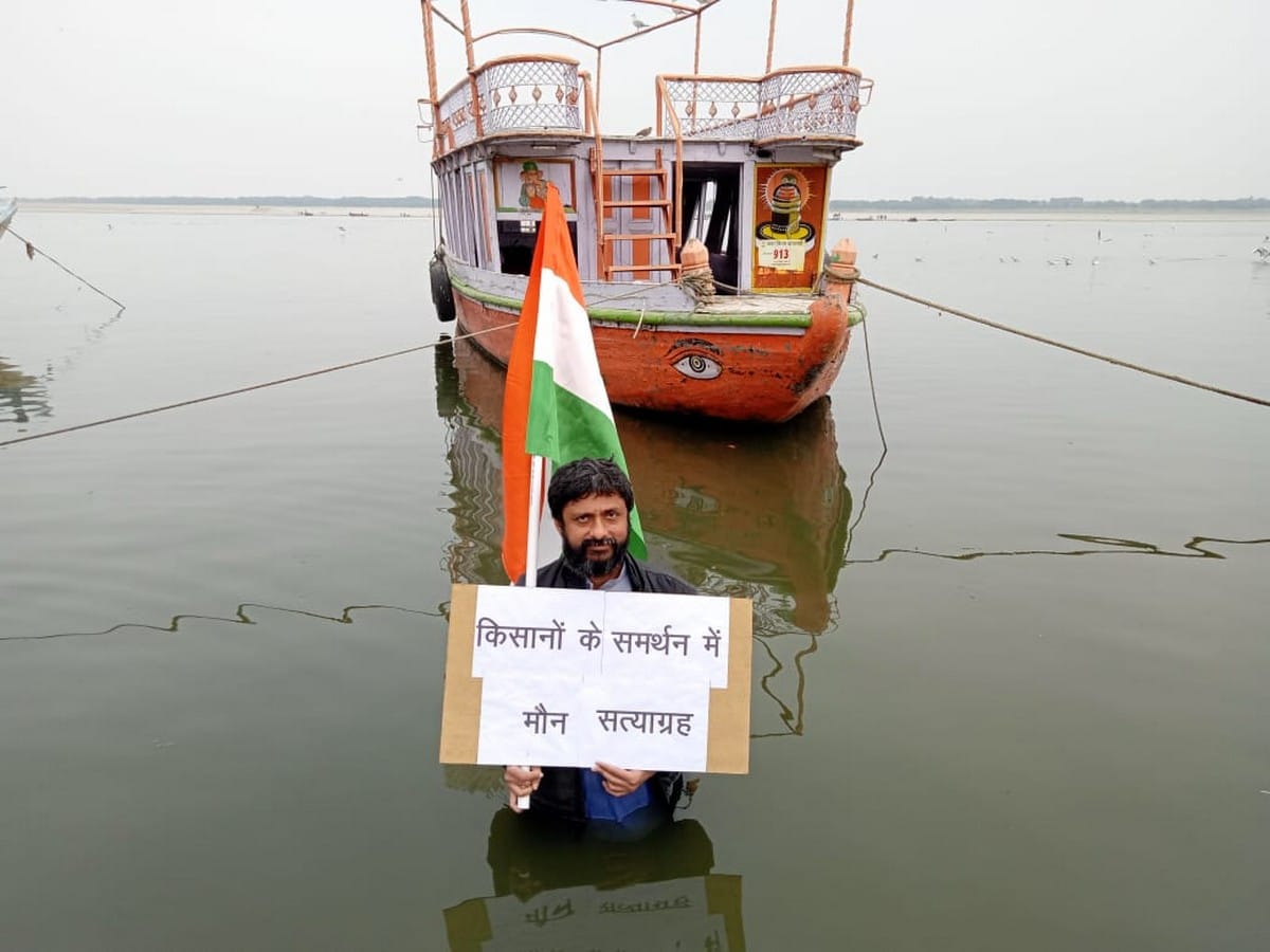 man standing in Ganga with tricolor and vow of silence in support of farmers in varanasi