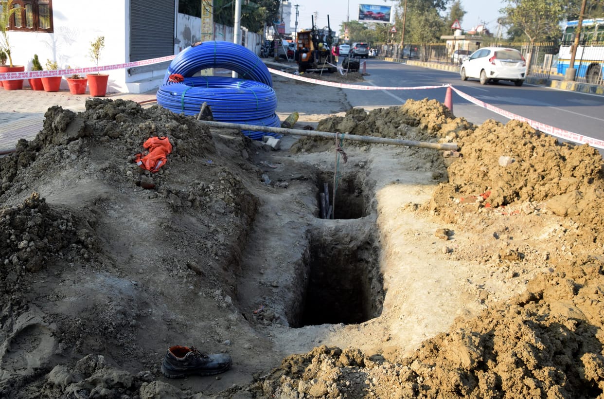 Two laborers laying telephone cables of private company buried in mud