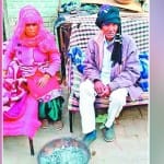 घर के बाहर बैठा बुजुर्ग दंपती।