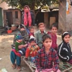 घर के आंगन में अपने आठ बच्चों के साथ चारपाई पर बैठी नाजरीन
