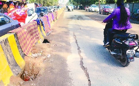 Road soil washed away by rain in front of corporation, pits along dividers