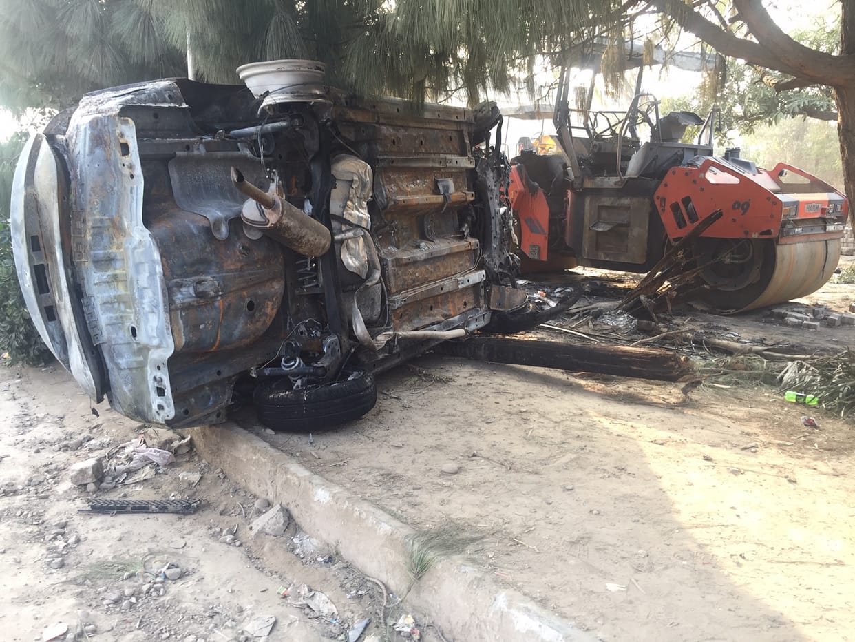 Burned car hit by road roller