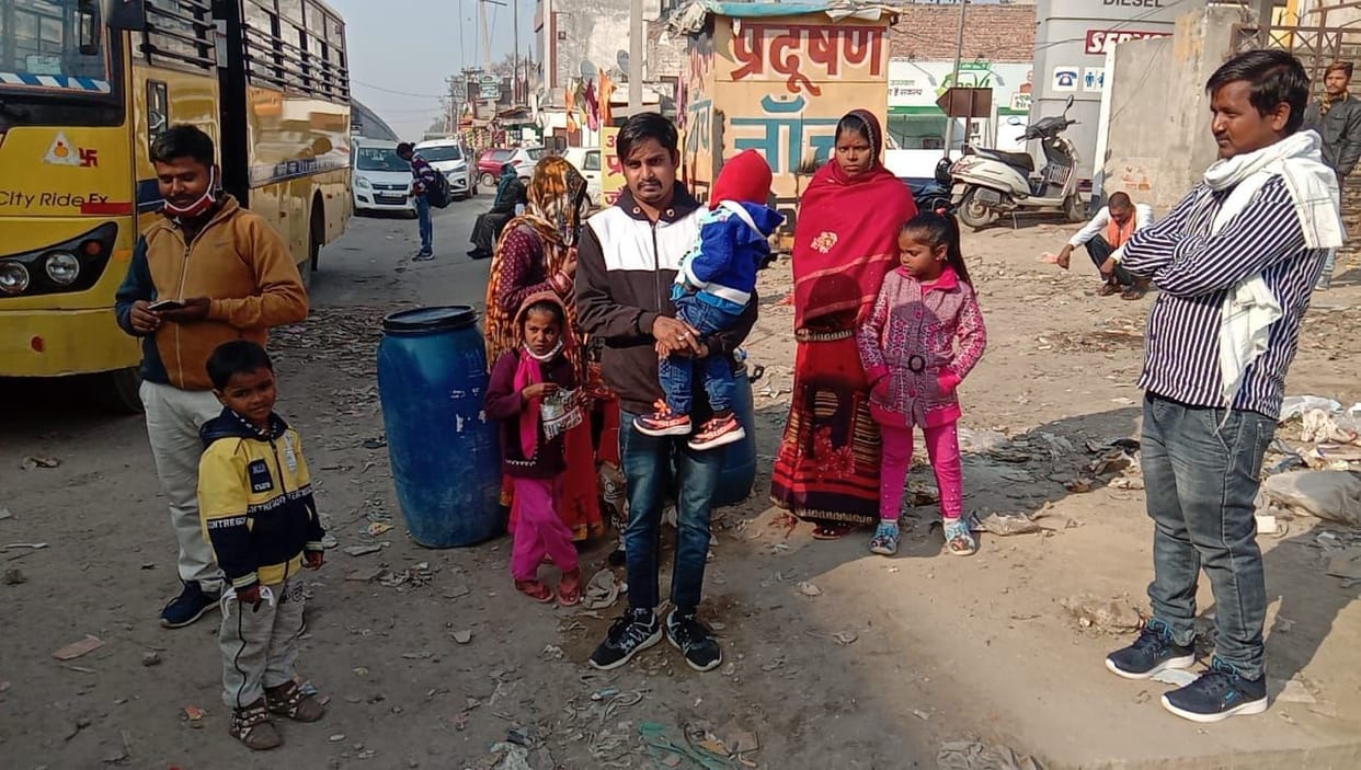 Migrants with children in their laps, bags on their heads