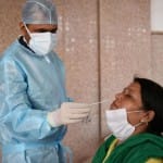 कोरोना जांच के लिए सैंपल लेता स्वास्थ्यकर्मी