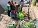 सिमलगैर उर्दू मिडियम स्कूल के पास खाली बर्तनों के साथ पानी का इंतजार करते लोग।