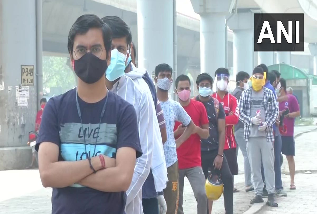 People form queues outside vaccination center at a government school in Badarpur