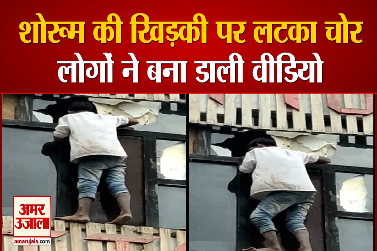 शोरूम की खिड़की पर लटका चोर