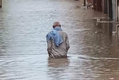 फतेहाबाद में बरसात से भरे पानी से गुजरता व्यक्ति।