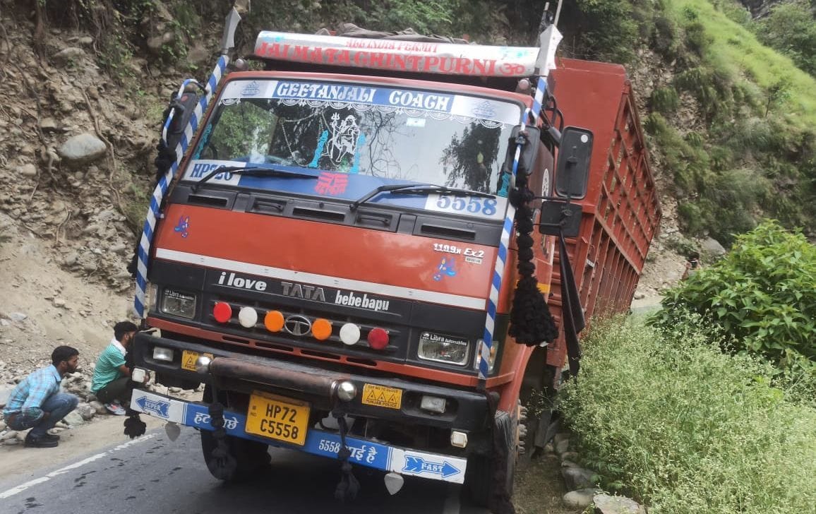 Truck laden with goods hanging off the road