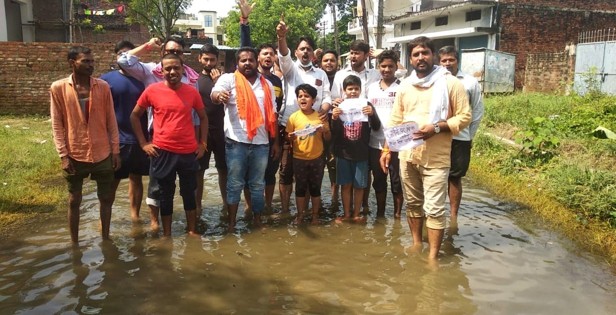 Standing in water to protest against the condition of the road