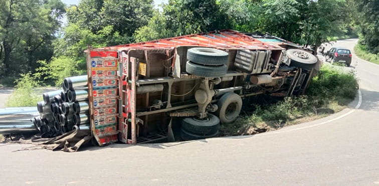 A truck laden with pipes overturned due to tire sinking in the pit