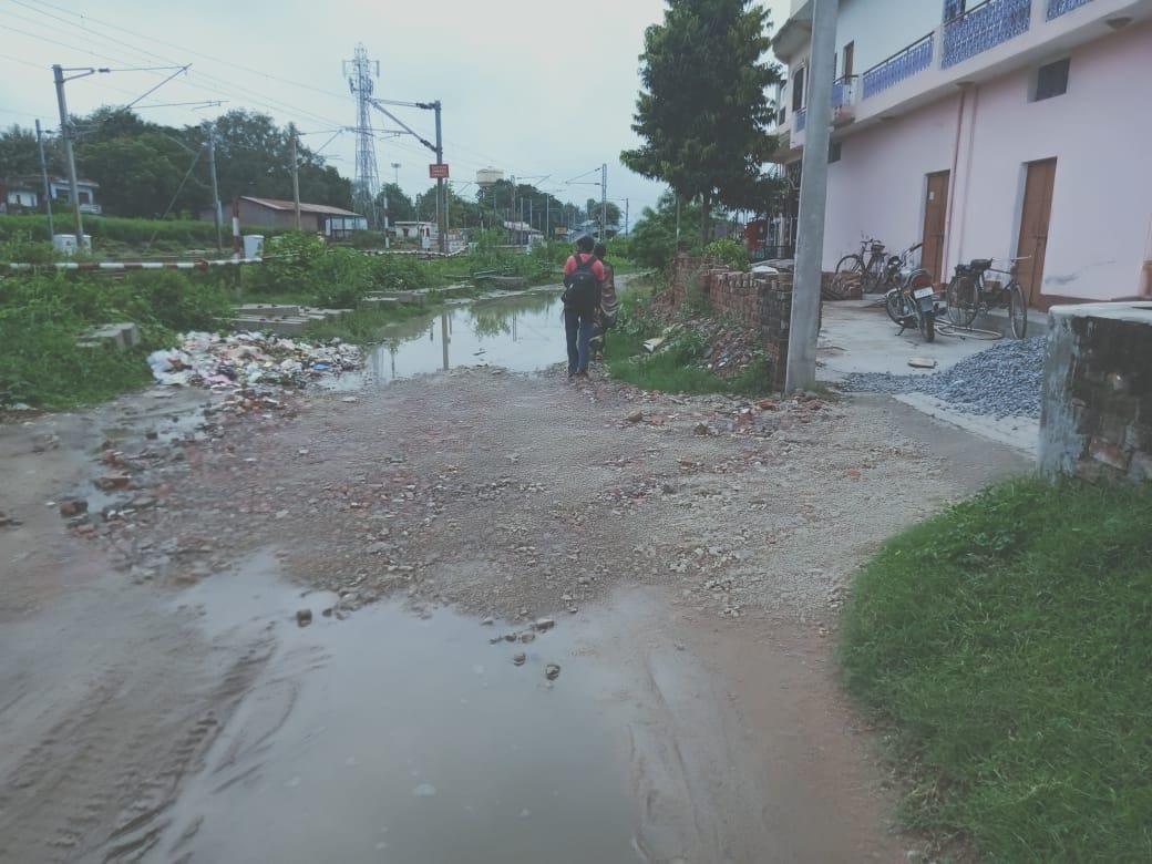 road is damaged people are crossing railway track