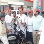 पेट्रोल पंप पर लोगों को फूल भेंट करते सपा नेता