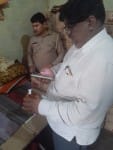 फोटो1 7एयूआरपी39- शराब की शीशी पर बने क्यू आर कोड को मोबाइल से स्कैन कर जांच करते जिला आबकारी अधिकारी