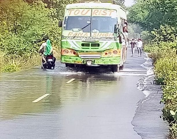 Road cut by flood water, traffic stalled