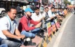 हल्द्वानी के तिकोनिया चौराहे के डिवाइडर पर बैठ बूट पॉलिश कर विरोध जताते एचपी कंपनी के श्रमिक।      ?