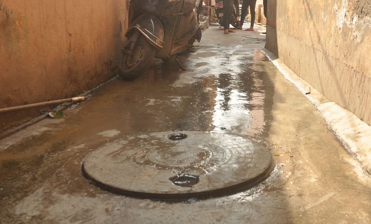 Dirty water flowing in front of houses due to sewer overflow, people upset