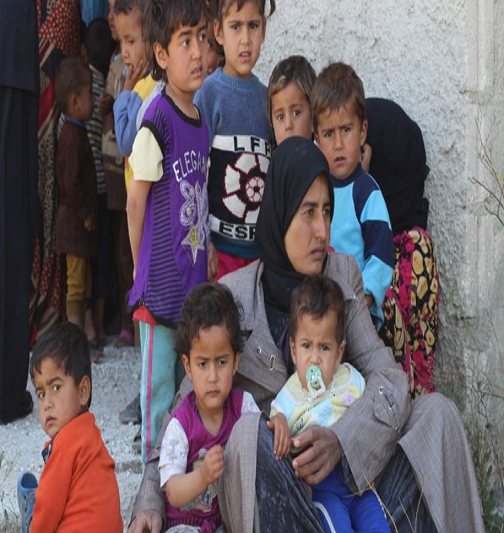 सीरिया के अलेप्पो के एक गांव में चिकित्सा केंद्र के बाहर अपने बच्चों के साथ एक महिला (फाइल फोटो)